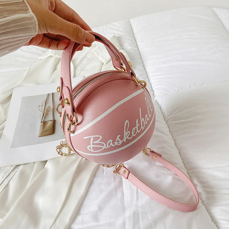 Pink basketball-shaped handbag with 'Basketball' text on a white surface