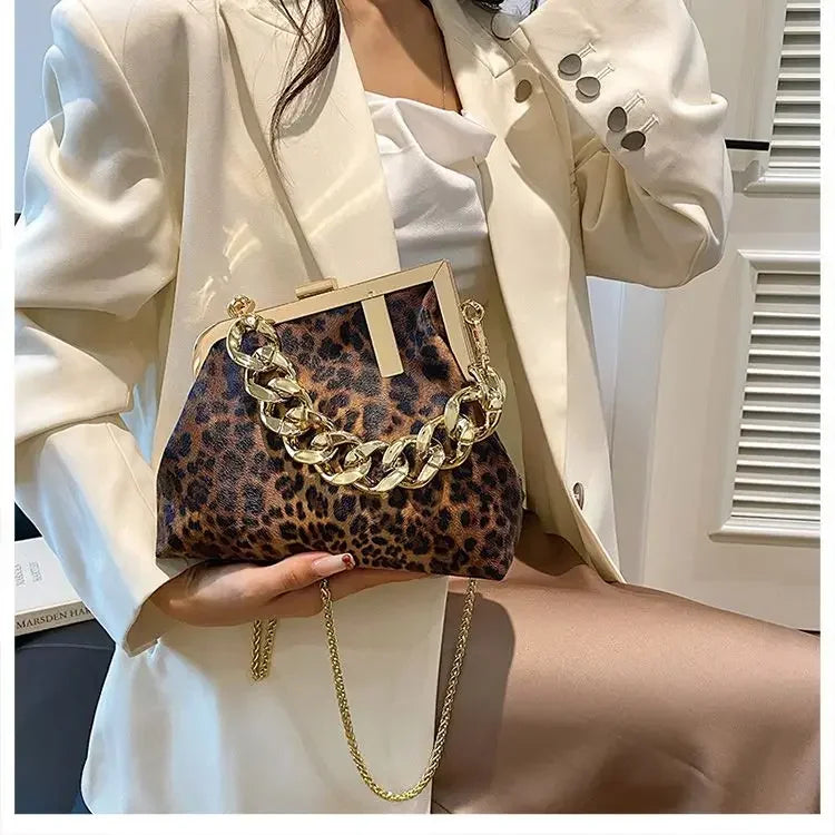 Person holding a Carauana_UNIU_Leopard_Clutch with gold chain detail