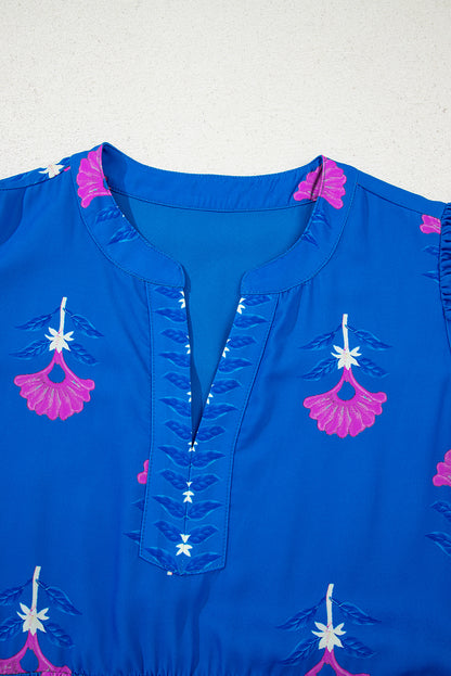 Blue top with pink and white floral embroidery on a light gray background