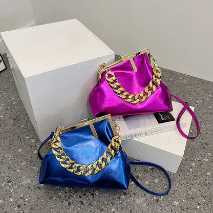 Carauana UNIU Aurora Clutch Two satin handbags with gold chains, one blue and one purple, on a gray surface.