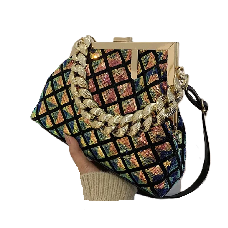 Multicolored patterned handbag with gold chain strap held by a hand on a white background