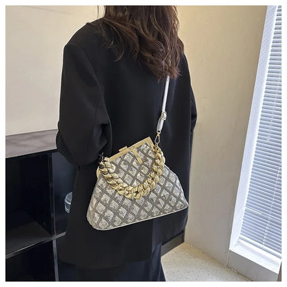 Person holding a silver handbag with a chain detail indoors.
