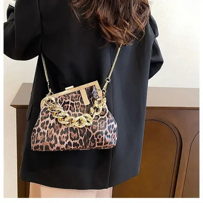 Person wearing a Carauana_UNIU_Leopard_Clutch with gold chain detail.