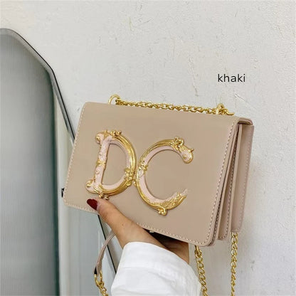Beige Dolce_CaRaUaNa handbag with gold chain and 'DC' logo held by a hand