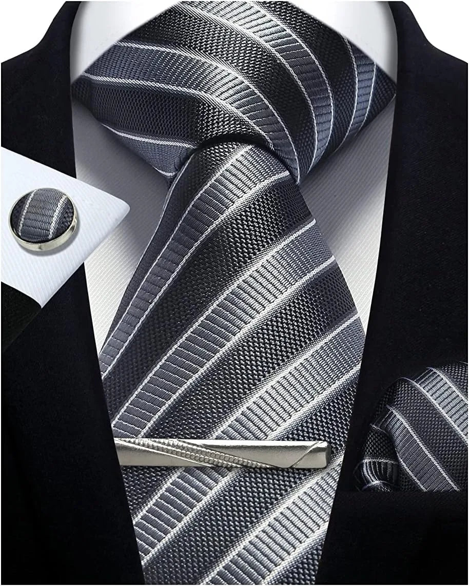 Gray striped tie with matching cufflinks and tie clip on a black suit jacket.